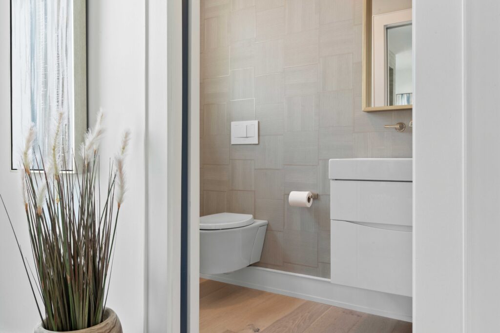 white toilet white vanity textured wall tiles tall plant