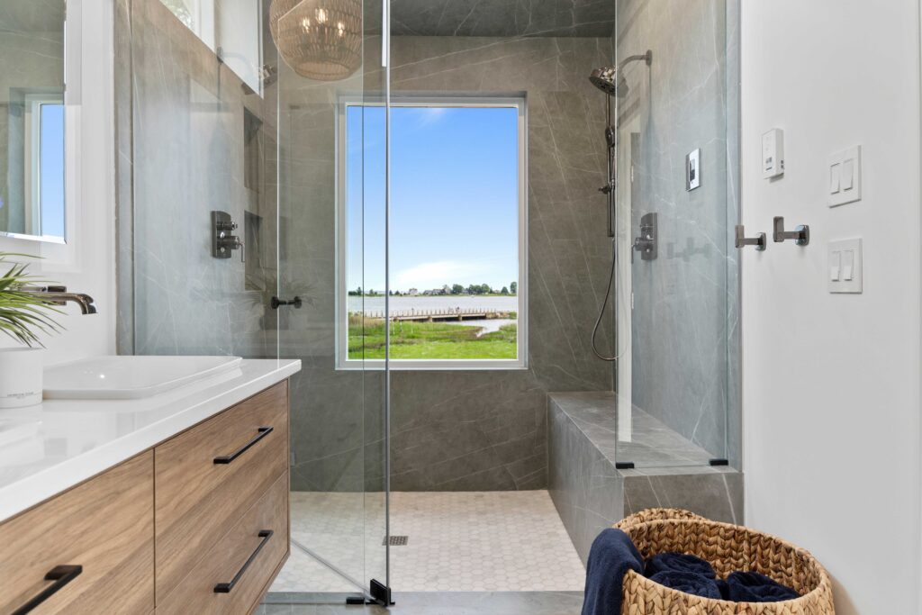 large glass shower, gray stone walls, wooden bathroom vanity with sink