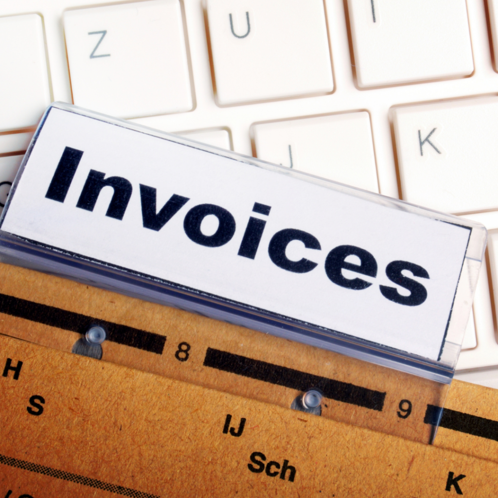 a sign that says Invoices sitting on top of a keyboard